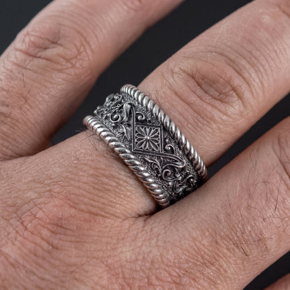 Viking wedding ring worn on a finger, showing the wide carved sterling silver band